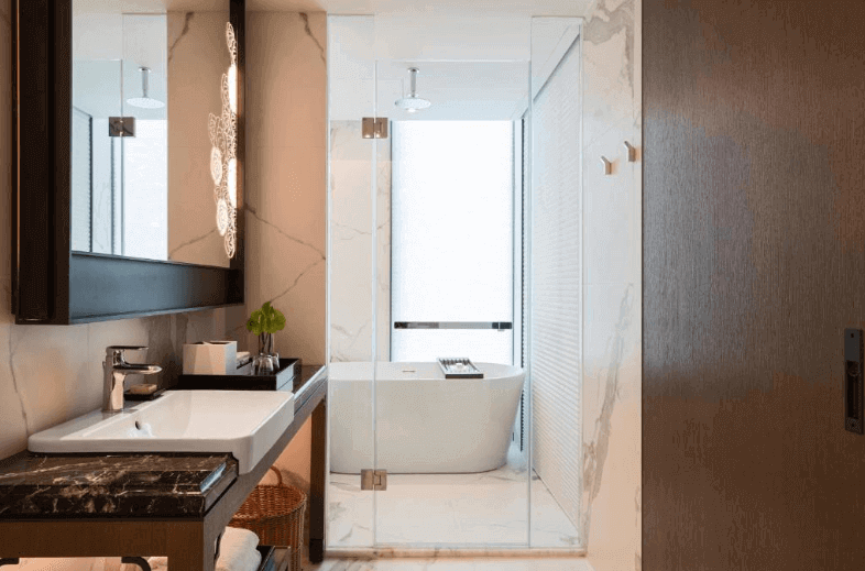 【台北親子飯店】台北士林萬麗酒店展示了一間豪華的浴室。浴室內有一個現代化的洗手台，上面擺放著日常用品。洗手台旁邊是一個獨立的浴缸，浴缸周圍有玻璃隔斷，增加了空間感。浴室的裝飾以白色大理石為主，顯得非常高雅和乾淨。整體設計注重細節和品質，給人一種奢華的感覺。