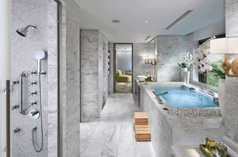 【台北親子飯店】台北文華東方的這是一間豪華客房的圖片，擁有一張大床，床頭牆採用了精緻的浮雕設計，增添了藝術感。房間內的照明溫暖柔和，並且窗外可以看到城市景觀。整體設計風格融合了現代與經典元素，給人一種高貴優雅的感覺。