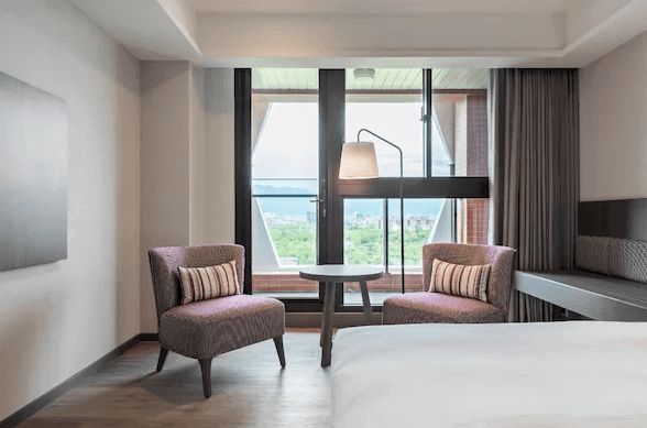 【宜蘭溫泉飯店】宜蘭館煙波大飯店的角落區域，設有兩張紫色的扶手椅和一張小圓桌，擺放在大窗戶旁邊。窗外可以看到綠意盎然的景色，光線充足，整體氛圍溫馨且適合放鬆。