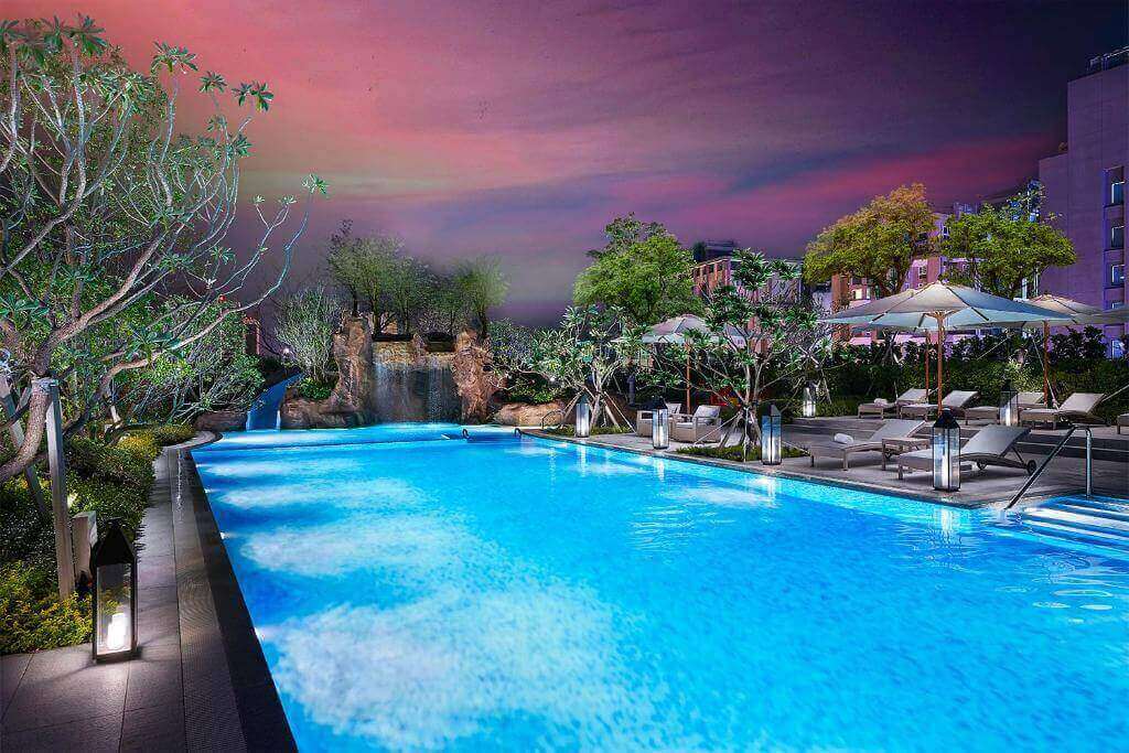 Resort-style outdoor pool with vibrant lighting, lounge chairs, and exotic landscaping at dusk