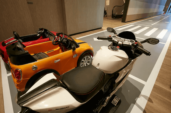 【宜蘭溫泉飯店】礁溪寒沐酒店的兒童遊戲區的場景，地上繪有道路和交通標誌，幾輛兒童遊樂用的玩具車和摩托車擺放在這裡。這個區域設計模擬了道路環境，供孩子們安全玩耍，充滿趣味性和互動感。