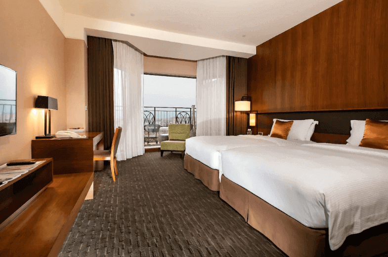 Elegant hotel room with two queen beds and a scenic balcony view, combining comfort with luxury