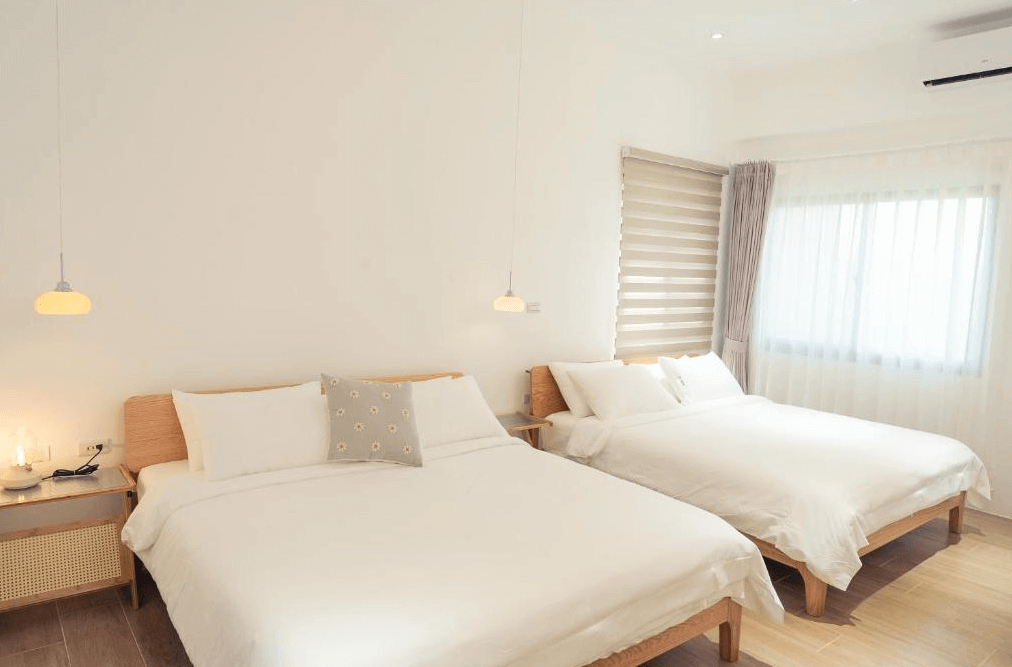 【美濃住宿】No.1899 人文旅宿的民宿房間，內部配有兩張雙人床，床頭上方掛有簡約的吊燈。房間的窗戶讓自然光充足，整體設計風格簡潔而舒適。