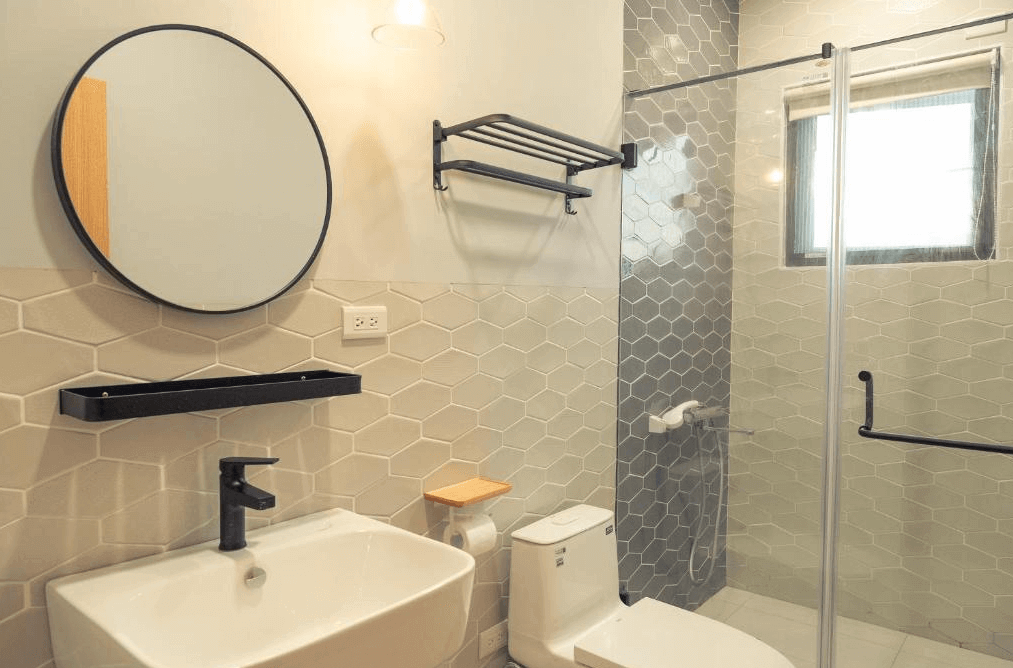 【美濃住宿】No.1899 人文旅宿的浴室，內部配有淋浴間、洗手台和馬桶。浴室的牆面採用六邊形瓷磚設計，裝飾簡約且具有時尚感，鏡子和置物架的設計實用而美觀。