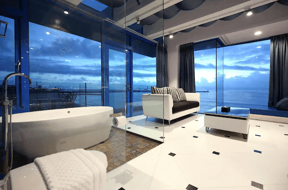 【花蓮市海景住宿】豪華的浴室設計，配有獨立浴缸和玻璃牆，能夠俯瞰海景。浴室與起居室相連，擁有現代感十足的設計風格和寬敞的空間，讓人可以一邊沐浴一邊欣賞外面的美景