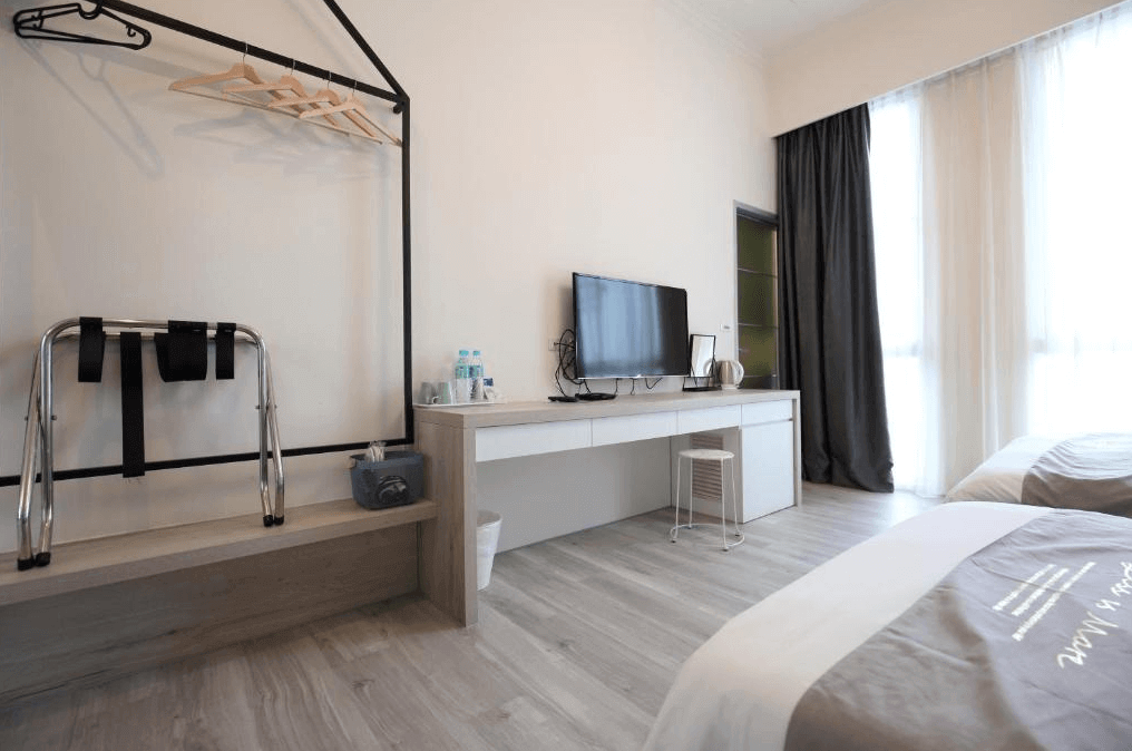 【花蓮市海景住宿】微藍海岸海景夜市電梯民宿的客房內設有雙人床和工作區，配有電視和書桌。房間內的衣架和行李架設計簡潔，為住客提供便利的收納空間。大窗戶讓自然光線充足，營造舒適的住宿環境