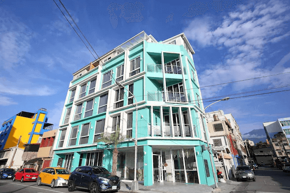 【花蓮市海景住宿】微藍海岸海景夜市電梯民宿的外觀，建築物採用明亮的藍色設計，位於熱鬧的街區。多層樓的建築提供多間客房，並設有大型窗戶，讓住客能夠享受充足的自然光和景觀