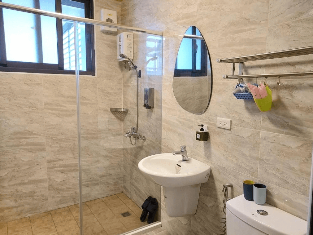 【玉里住宿】時雨民宿的浴室，設有玻璃淋浴間和白色洗手台，牆面覆蓋著淺色瓷磚，乾淨明亮，配備基本的衛浴用品。