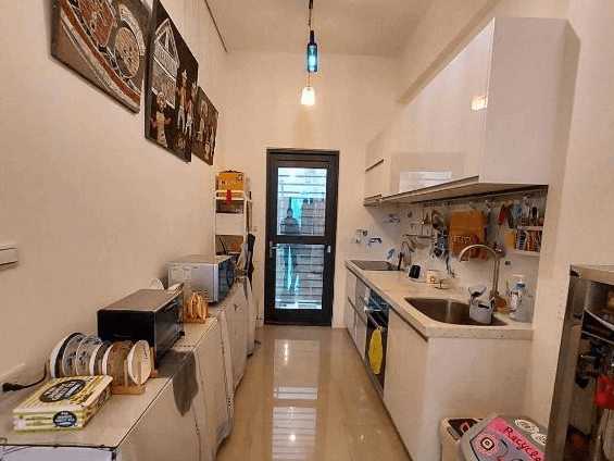 【玉里住宿】時雨民宿的廚房，擁有長條形設計，配備多種廚具和電器，牆上掛著幾幅藝術畫，整潔有序，適合家庭使用。