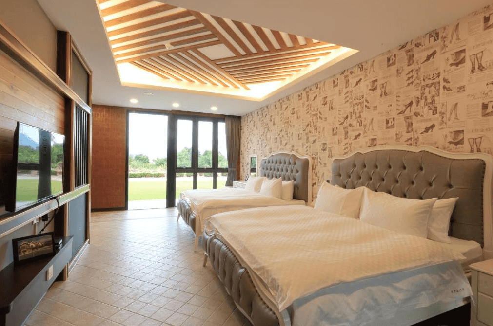 東戀溫泉民宿的雙人房，內有兩張大床，牆壁上裝飾著復古報紙風格的壁紙。房間內設有大型落地窗，提供充足的自然光和美麗的戶外景色。天花板設計精美，增添了空間的質感。