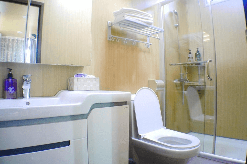 【美濃住宿】美濃涵園民宿的浴室，配有淋浴間、洗手台和馬桶。浴室內部裝飾簡約，採用木質牆面和玻璃門，提供乾淨整潔的使用空間。