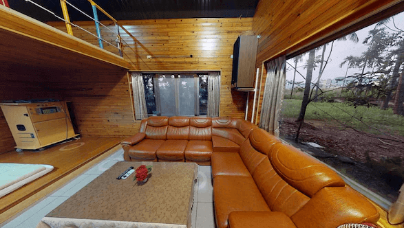 【美濃住宿】美濃百果園民宿的客廳區域，配有大型皮質沙發和低矮的咖啡桌。客廳的牆壁和天花板均以木材覆蓋，窗外可以看到庭院和樹木，營造出溫馨的自然氛圍