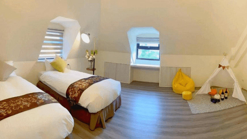 虎爺溫泉渡假莊園的雙人房，內有兩張單人床，房間寬敞明亮，設有大窗戶。房間內角落布置了兒童帳篷和豆袋椅，為小朋友提供了娛樂空間，整體設計溫馨且適合家庭入住。