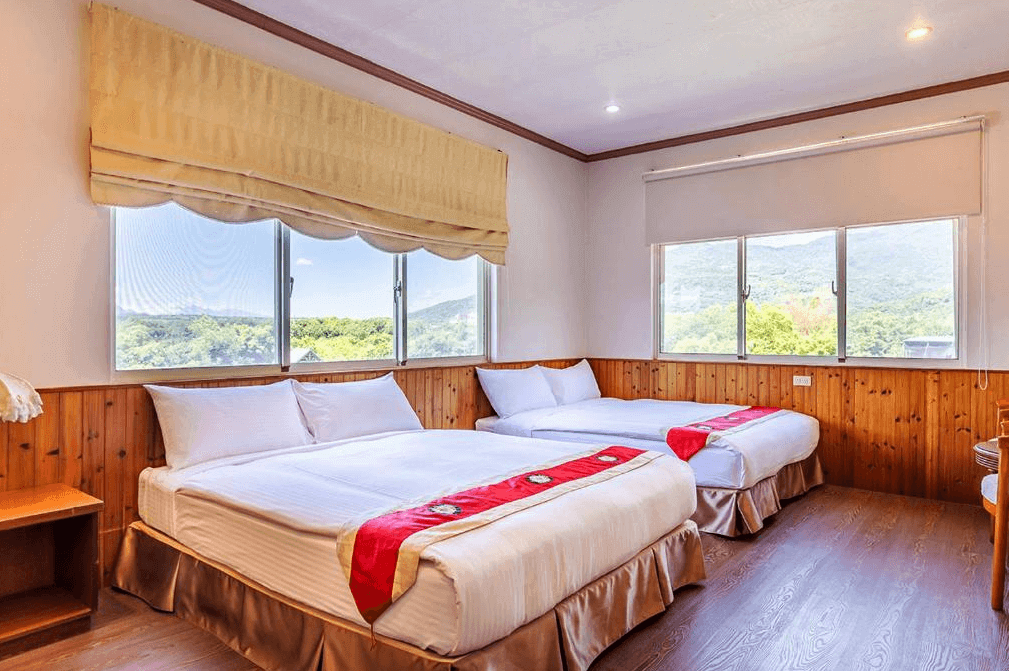 虎爺溫泉渡假莊園的景觀雙床房，內有兩張雙人床，床頭背景牆為木質設計。房間內設有多個窗戶，提供充足的自然光和美麗的山景，整體裝潢簡潔大方，讓人感到舒適放鬆。