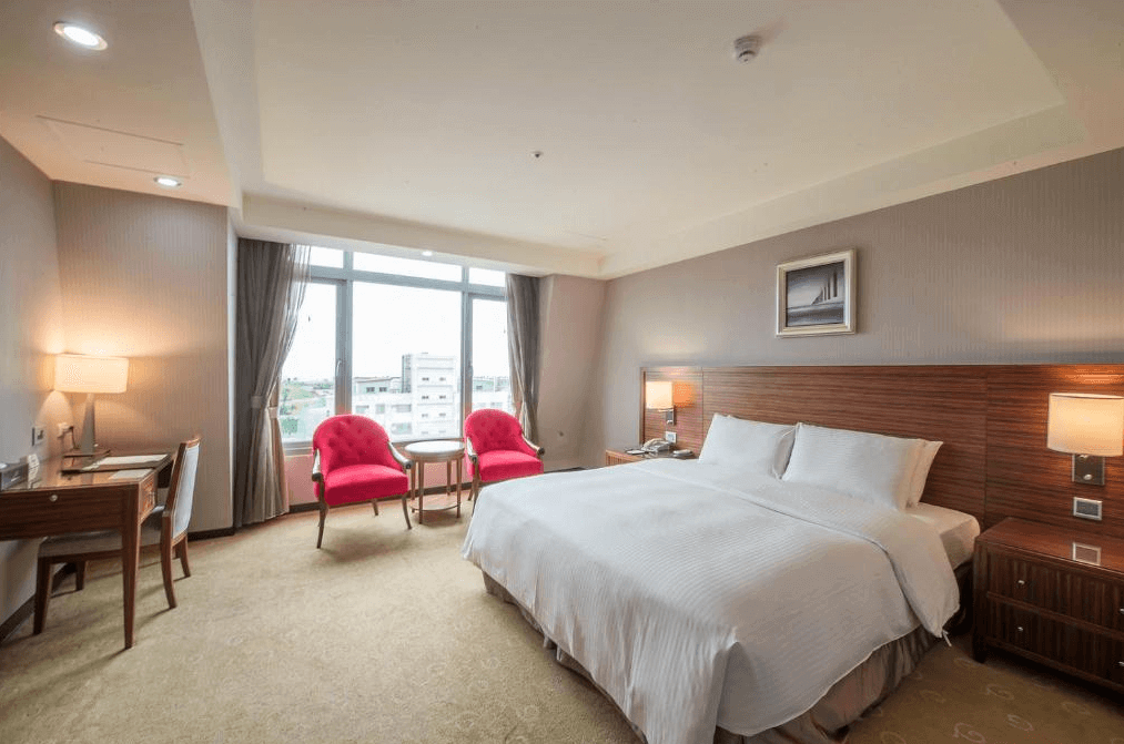 阿思瑪麗景大飯店的雙人房，房內設有一張大床，旁邊有兩張紅色扶手椅和圓桌，窗外景色怡人，房間設計溫馨典雅