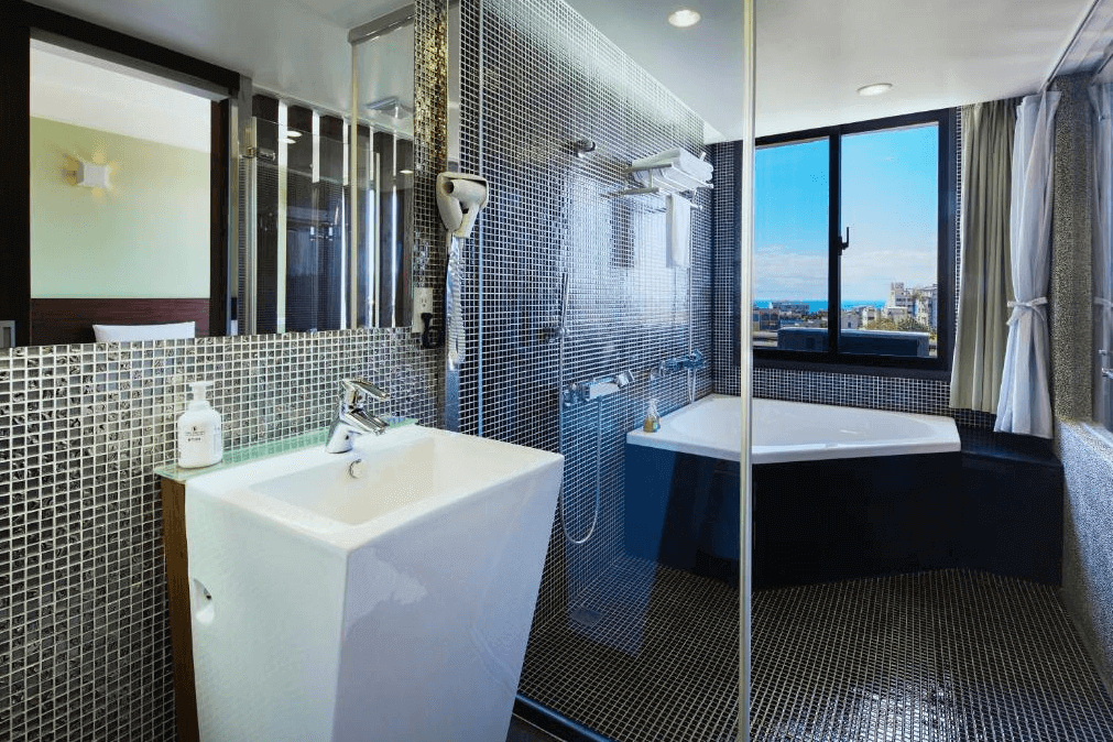 麗翔酒店連鎖花蓮館的現代化設計的浴室，配有玻璃淋浴間和大型浴缸。牆面採用小瓷磚設計，提供充足的自然光，讓空間顯得明亮且高雅