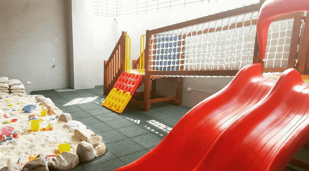黃色風箏的一個設有滑梯和沙坑的室內遊樂區,配有各種兒童玩具,適合孩子們在安全環境中盡情玩耍,提供家庭旅客便利的設施。
