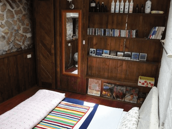 【九份寵物友善住宿】九份寧靜海芳療民宿的雙人房，房間內設有一張雙人床，床上鋪有彩虹條紋的被褥。房間內有大面積的窗戶，窗外可見綠意盎然的自然景觀，營造出溫馨舒適的氛圍。