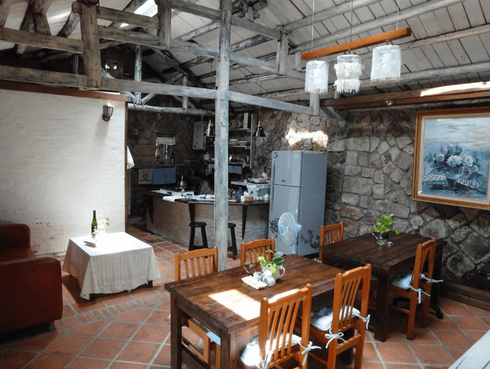 【九份寵物友善住宿】九份寧靜海芳療民宿的臥室，房間內設有木質書架，擺放著各種書籍和盥洗用品。床上鋪有彩虹條紋的被褥，牆壁以紅磚和木材裝飾，營造出溫暖的居家感。