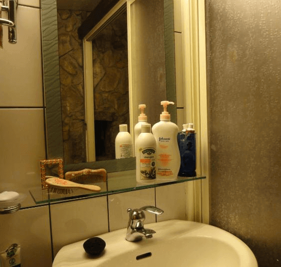 【九份寵物友善住宿】九份寧靜海芳療民宿的公共用餐區，內部設有木質桌椅，牆壁以石材裝飾，呈現出自然古樸的風格。區域內有一個開放式廚房和一幅掛畫，整體空間明亮寬敞。