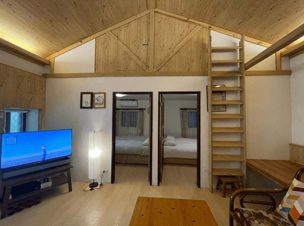 【九份寵物友善住宿】九份金瓜石樹屋的家庭房，房間內有兩間臥室和一個開放式的客廳。客廳內設有一台大電視和舒適的沙發，並配有一個木質樓梯通往閣樓。