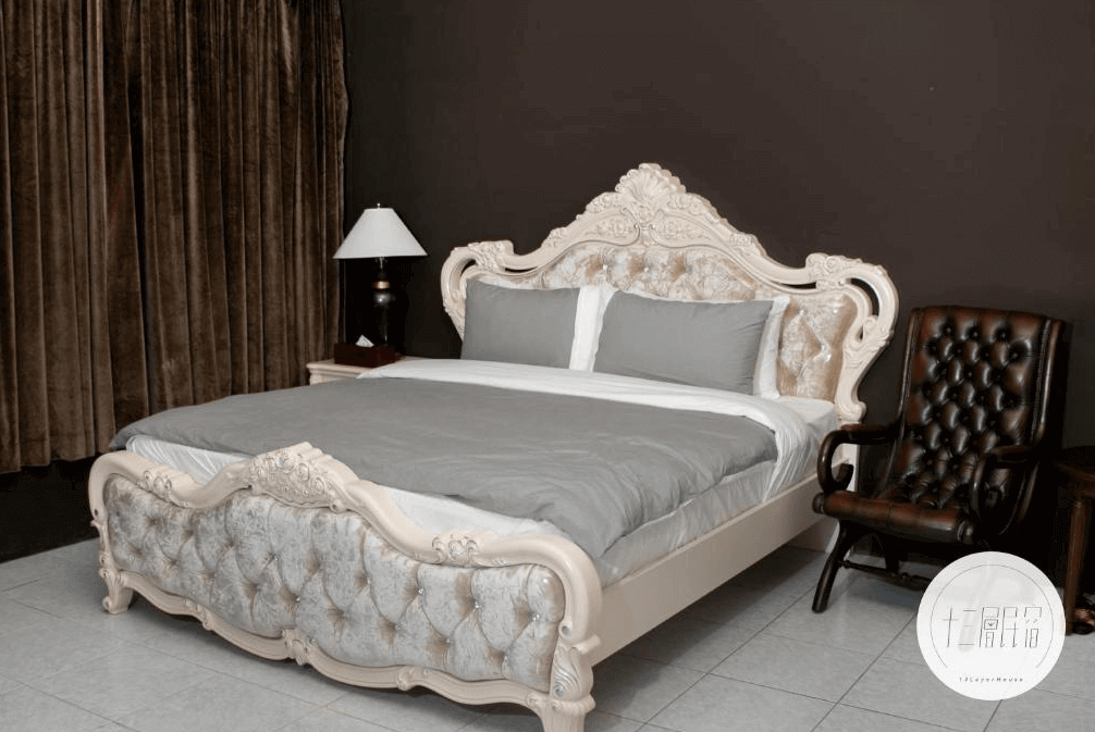 【九份寵物友善住宿】十三層民宿的豪華雙人房，房間內設有一張裝飾精美的古典風格大床，床頭兩側各有一盞床頭燈。房間角落擺放了一張深棕色的皮質扶手椅，窗簾為深色系，整體設計高雅大方。