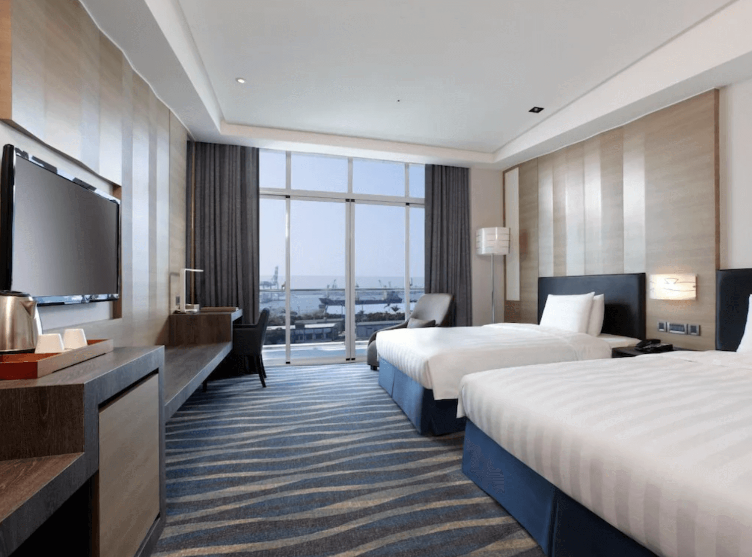 城市商旅高雄真愛館的雙床海景房，房間內設有兩張單人床，寬敞明亮。落地窗外可欣賞到美麗的海景，讓賓客在房間內即可享受高雄港的景色。房內還配有書桌和現代化設施，提供舒適的住宿環境