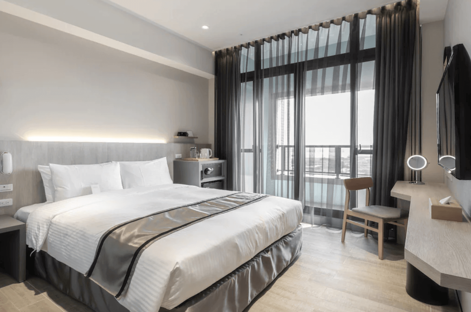 塩 • 泊思行旅的雙人房，房間內設有一張大床，床鋪整潔舒適。落地窗設計使房間內光線充足，窗簾可調節光線，提供良好的隱私保護。房內還設有電視、書桌和基本生活設施，為賓客提供舒適便利的住宿環境