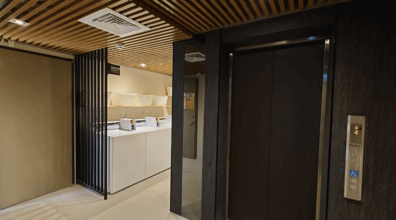 塩 • 泊思行旅的洗衣區，洗衣區內設有洗衣機和烘乾機，供賓客自由使用。空間設計簡約實用，木質天花板和黑色金屬隔板增添了現代感，讓賓客在住宿期間能享受到家一般的便利