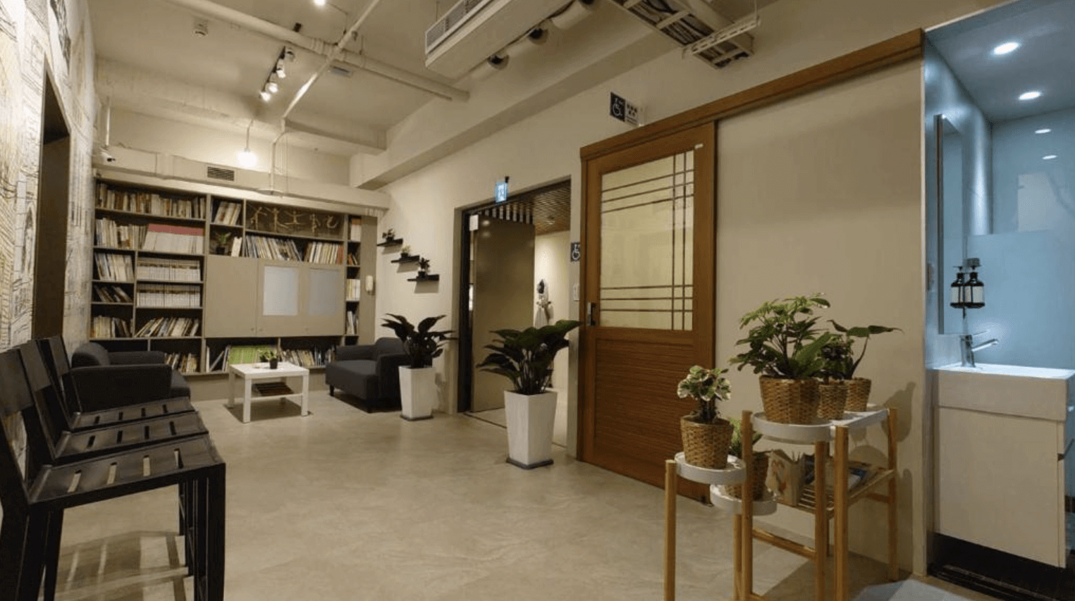 塩 • 泊思行旅的公共休息區，休息區內設有舒適的沙發和大量的書籍，為賓客提供了一個放鬆和閱讀的理想場所。空間設計溫馨，擺放了綠色植物，營造出舒適宜人的環境，讓賓客能夠在這裡享受悠閒時光