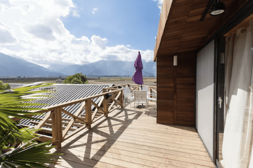 【池上民宿】好和院景HowHas陽台上的木製露台，擁有寬敞的空間和美麗的山景。一把紫色遮陽傘和白色戶外桌椅，營造出舒適的休閒氛圍。晴朗的天空和遠處的山脈使得這裡成為欣賞自然景色的理想地點