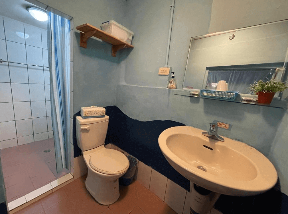 【九份寵物友善住宿】望幽谷民宿的浴室，牆面以藍色為主，設有一個洗手台和馬桶。浴室內有一個獨立淋浴間，空間雖小但功能齊全，提供乾淨舒適的衛浴環境。