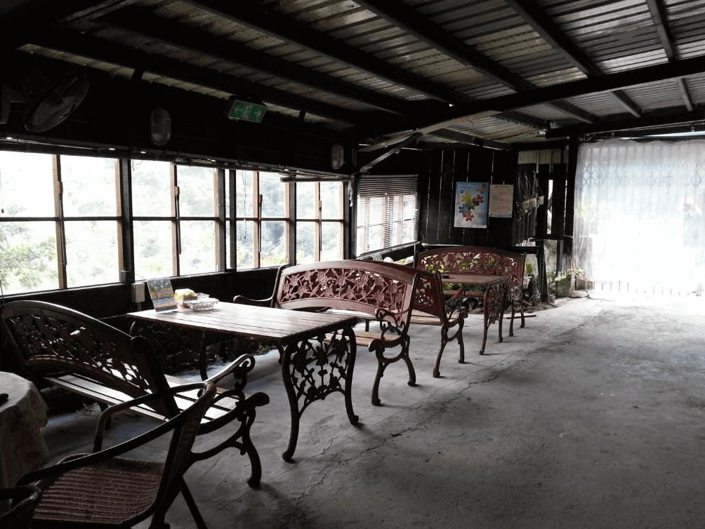 【九份寵物友善住宿】望幽谷民宿的戶外休息區，設有多組鐵藝桌椅，周圍被綠意盎然的自然景觀環繞。區域內光線充足，是放鬆休憩的理想場所。