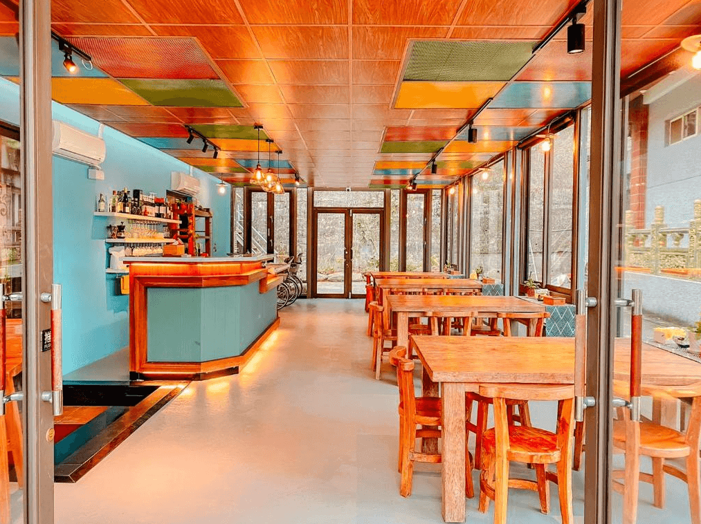 湖畔46民宿展示了湖畔46民宿的餐廳，餐廳內設有多張木製桌椅，彩色天花板和溫暖的燈光營造出溫馨的氛圍。餐廳的一角還設有一個吧台