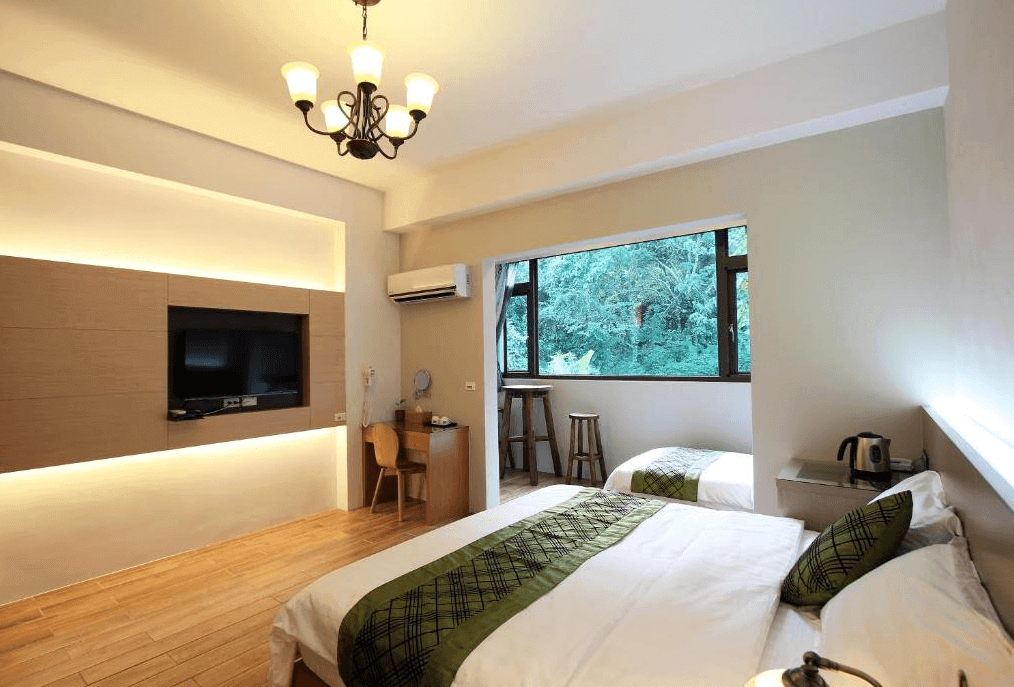 湖畔46民宿展示了一間雙人床房，房間內設有兩張雙人床，床頭上方裝有古典風格的吊燈，房間內還設有平板電視和工作桌。窗外可以看到綠樹成蔭的風景