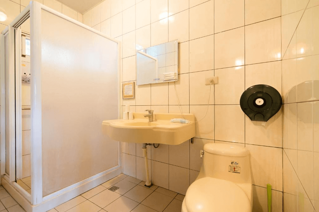 花蓮莫內花園民宿展示了一間簡潔的衛生間，內有一個淋浴間、洗手台和馬桶。牆面採用白色瓷磚，整體設計簡約且功能齊全