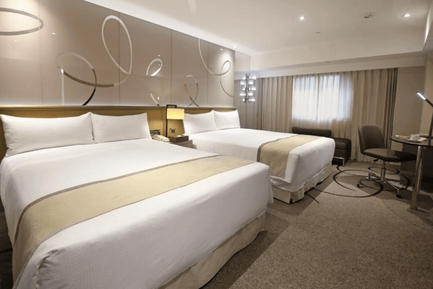 【高雄親子飯店】高雄翰品酒店的雙床房，房間內設有兩張大床，適合家庭或朋友同行入住。牆面設有簡約現代的裝飾圖案，整體色調柔和，營造出舒適的住宿氛圍。房間內部寬敞明亮，提供舒適的住宿體驗