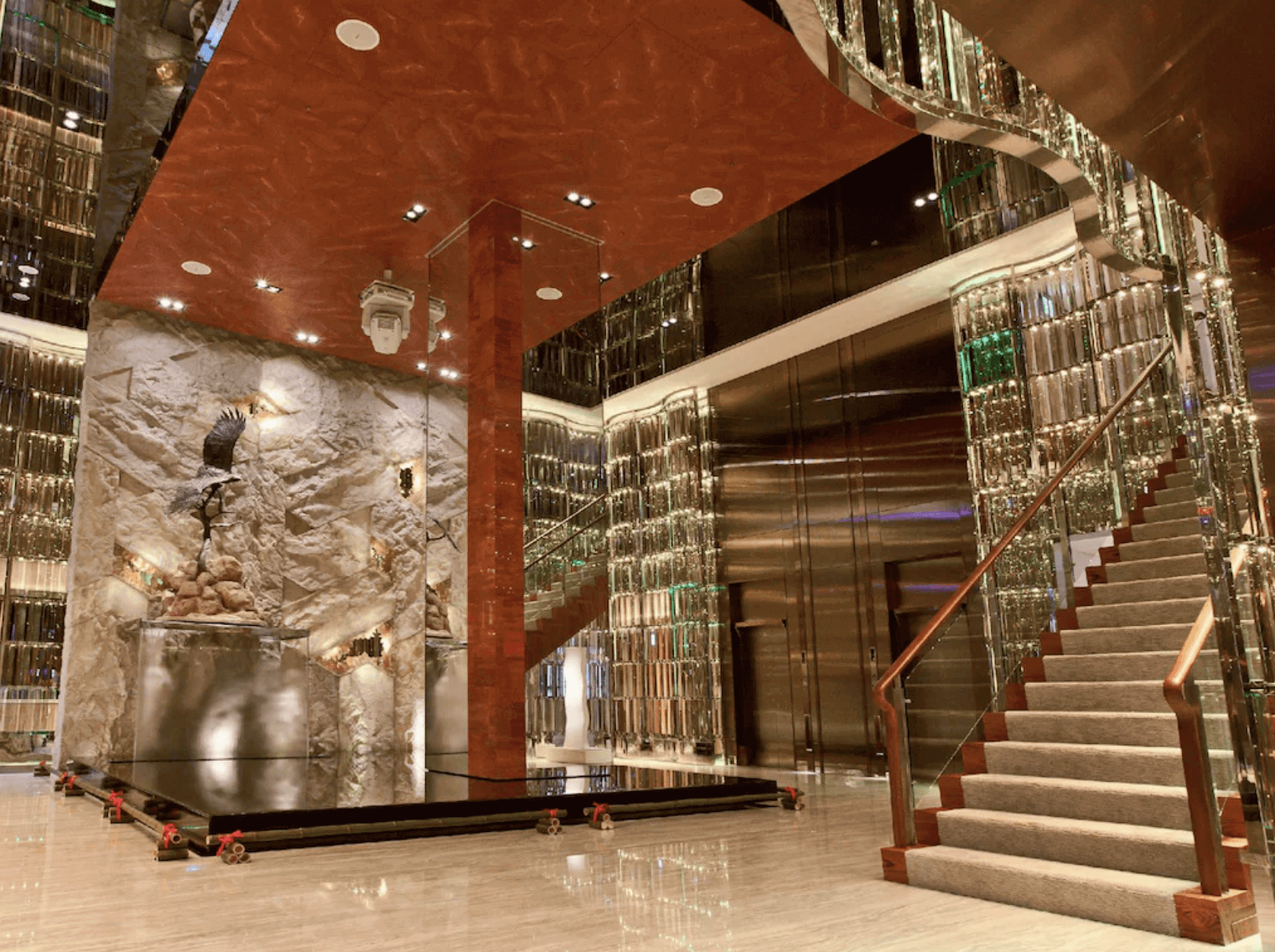 【高雄親子飯店】高雄翰品酒店的大廳，大廳設計豪華且現代。採用鏡面和石材裝飾，營造出寬敞明亮的空間感。樓梯和裝飾雕塑增添了藝術氛圍，是賓客抵達酒店時的第一印象