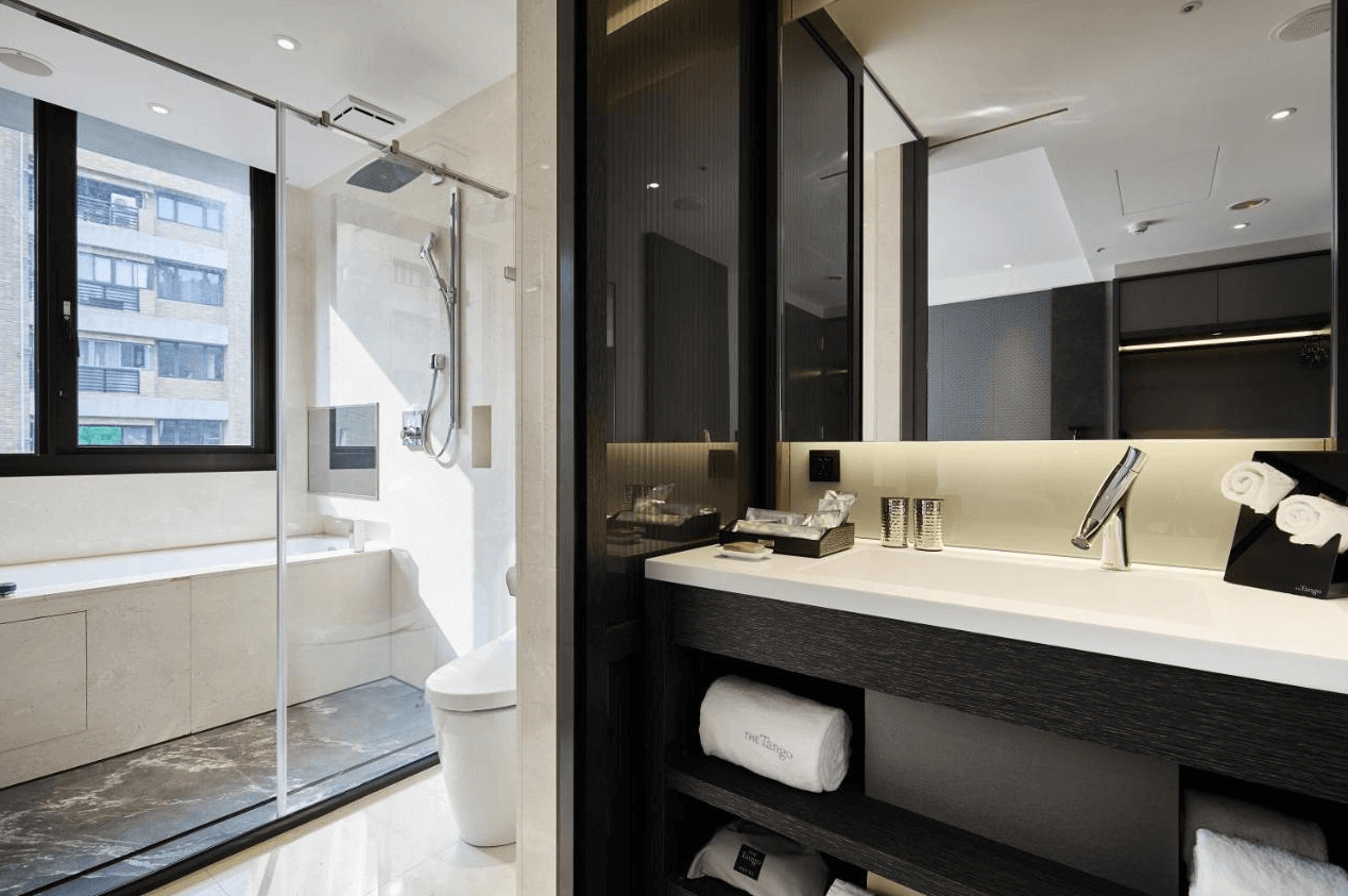 天閣酒店-台北劍潭館展示了酒店的現代化浴室設計。浴室內有大窗戶，可以看到外面的景色，配備淋浴間和獨立的浴缸。洗手台設計簡約且實用，提供了充足的收納空間和乾淨的設施。