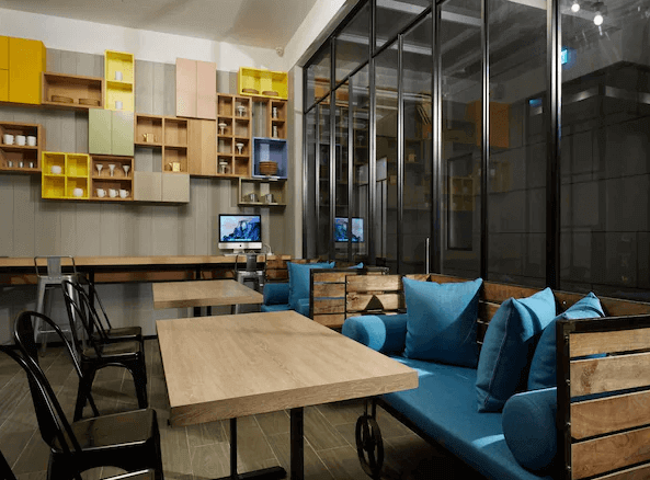 天雲旅棧-台北基河展示了一間現代風格的公共區域，內有多張木製桌椅，供客人使用。牆上裝飾著色彩豐富的儲物櫃，增加了空間的趣味性。整個空間設計簡約大方，色調溫暖，給人一種舒適和愜意的感覺。這裡非常適合客人在此休息、工作或交流。