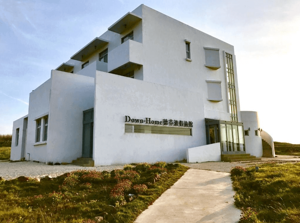 德芬渡假旅館的外觀,建築物採用白色牆體設計,風格現代且簡約。前方有一條小徑通往入口,四周綠地環繞,環境優美寧靜。