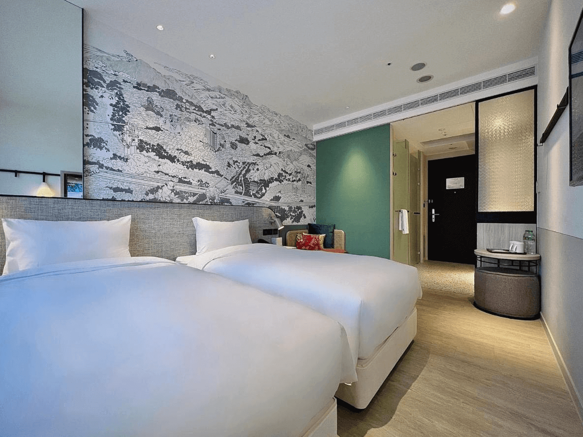 見潭璞旅的一間設有兩張雙人床的現代化客房，牆上有一幅黑白風景畫。房間的設計風格簡約，床頭牆是灰色的，右側有一張帶靠墊的小沙發，左側是一張小圓桌。