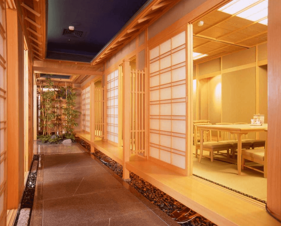 "台北小巨蛋住宿"兄弟大飯店的傳統日式風格的走廊，採用木質裝飾，兩側有著紙拉門，帶有濃厚的日式元素。走廊地面鋪有石板，邊緣點綴著竹子和小石頭，營造出日式庭院般的氛圍，空間感平和且充滿禪意。