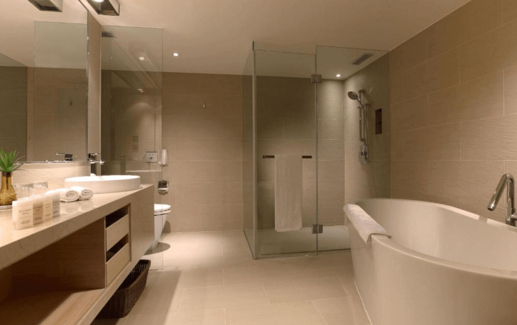 【松山機場住宿】和逸飯店-台北民生館的浴室圖片，浴室內配有獨立式浴缸和玻璃淋浴間，空間寬敞明亮。洗手台設計簡約，鏡子和台面整潔有序，牆面和地面都使用了淺色瓷磚，營造出乾淨、舒適的氛圍，適合放鬆身心。