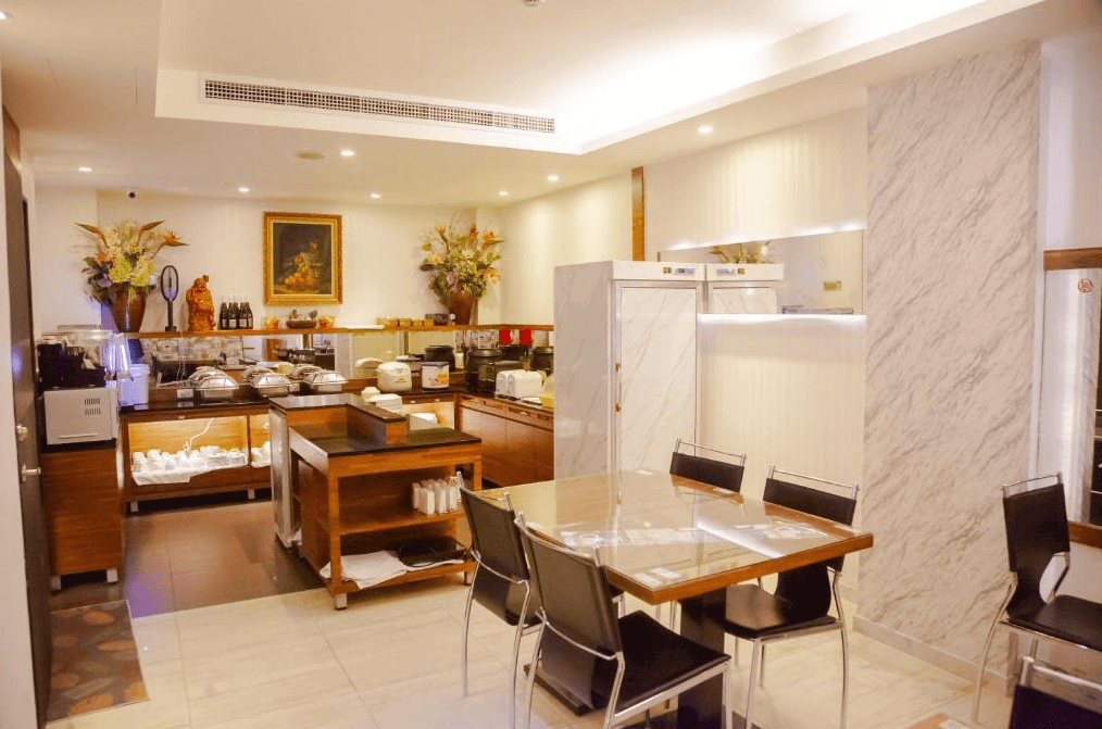 餐廳自助餐區的照片，展示了擺放整齊的餐具和多種早餐選擇，餐廳內部裝飾有花藝作品和壁畫，空間明亮且布置典雅。