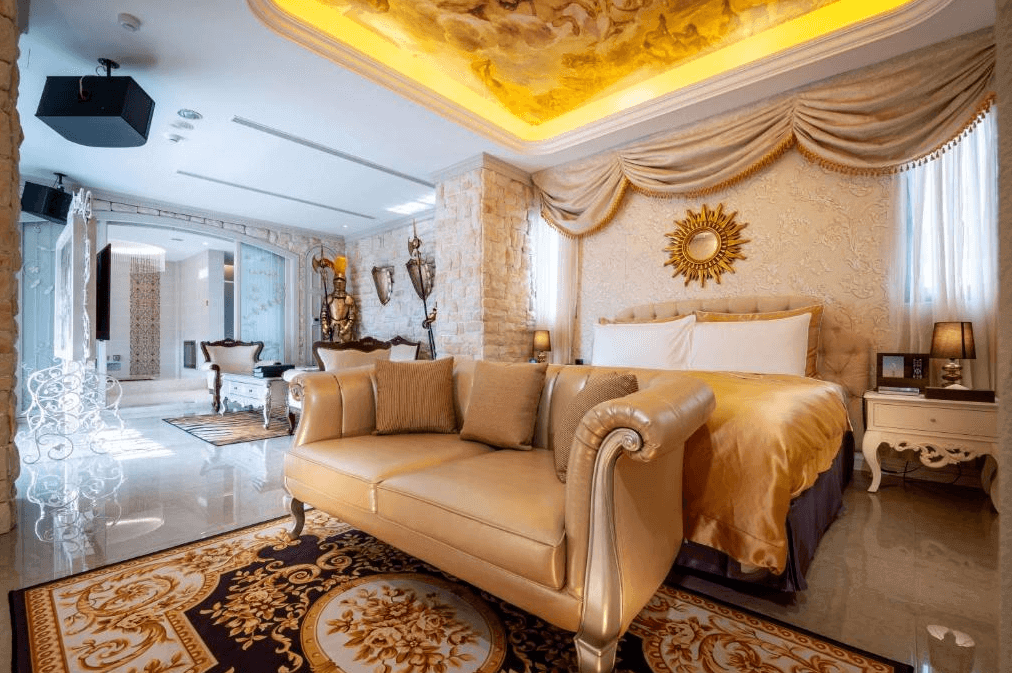 【台中情趣汽車旅館】極光情境旅館房間設計豪華且充滿古典風情，擁有華麗的床和優雅的沙發。天花板上的壁畫和華麗的裝飾增添了房間的高貴感。房間內的燈光設計巧妙，提供溫馨且浪漫的氛圍。