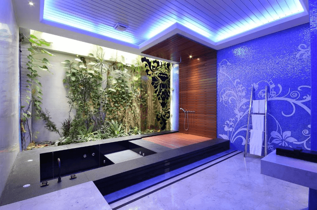 【台中情趣汽車旅館】沐蘭精品旅館台中館浴室設計現代且時尚，牆面裝飾著藍色馬賽克瓷磚，營造出清新亮麗的氛圍。浴池旁邊有綠色植物裝飾，讓人感到放鬆和愉悅。天花板的照明設計增添了整體的現代感和舒適度。