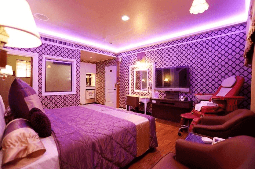 【新營汽車旅館】温莎堡汽車旅館新營館的房間以紫色為主色調，背景牆和床上用品皆採用紫色設計，房內設有一張大床、一個化妝桌、紅色按摩椅和舒適的座椅，整體風格華麗且充滿情調。