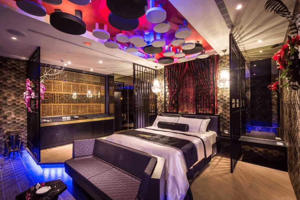 【台中情趣汽車旅館】紫禁城MOTEL主題會館房間的設計融合了中式風格和現代元素，擁有豪華的裝飾和獨特的燈光設計。床頭牆面裝飾著傳統的中國花格，天花板上裝飾著圓形的吊燈和現代感十足的燈飾。整體氛圍高雅且富有異國情調。