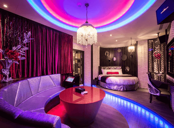 【台中情趣汽車旅館】紫禁城MOTEL主題會館房間設計充滿奢華感，擁有圓形的床和沙發區。天花板和牆面的燈光設計精妙，營造出浪漫和現代感。紅色窗簾和金色裝飾使房間更加華麗，適合浪漫度假或特殊場合入住。